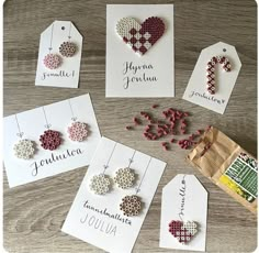 several different types of earrings and tags on a wooden table next to some paper bags