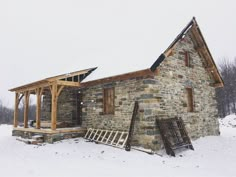 an old stone building with snow on the ground and stairs leading up to it's roof