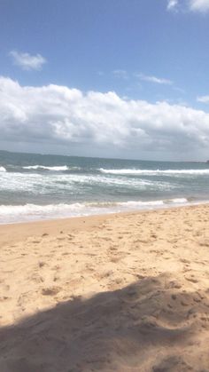 a surfboard sitting on top of a sandy beach next to the ocean with waves coming in