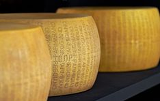 three large yellow cheese wheels sitting on top of a shelf next to eachother