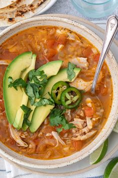 a bowl of chicken tortilla soup with avocado and cilantro