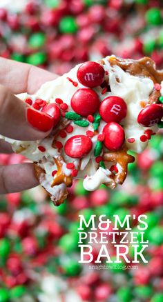 a hand holding a piece of m & m's pretzel bark with cherries on it