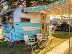 an old camper is parked under a awning with chairs and a bike in the foreground