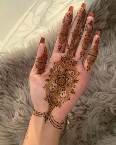 a woman's hand with henna tattoos on it, showing the intricate design