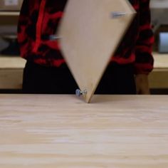 a person standing at a table with a piece of wood on it