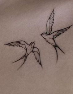 two small birds flying next to each other on a white sheet with black ink in it