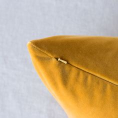 a close up view of a yellow pillow on a white surface with a gold zipper