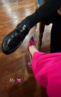 a woman in pink dress and black shoes sitting on a chair