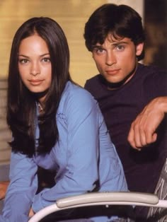 the young man and woman are sitting next to each other in front of a car