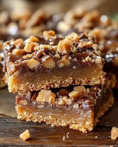 three pieces of chocolate caramel pecan bar stacked on top of each other with walnuts