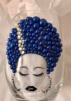 a wine glass decorated with blue beads and a woman's face