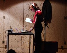 a woman standing in front of a laptop computer on top of a desk next to a microphone