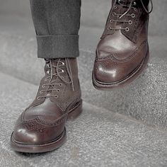 a close up of a person's foot wearing brown shoes on some concrete steps