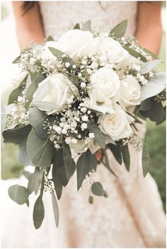 a bridal holding a bouquet of white flowers and greenery