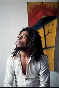 a man with dreadlocks looking up in front of a painting