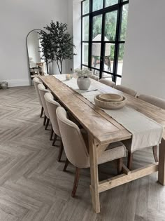 a dining room table with chairs and a bowl on top of it in front of a large window