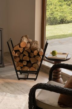 a stack of logs sitting in front of a window next to a chair and table