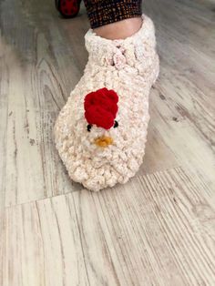 a child's feet wearing crocheted slippers with a chicken on them