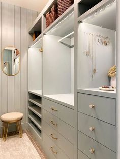 a walk - in closet with drawers, shelves and stools next to a mirror