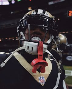 a football player wearing a helmet and holding a pair of pliers in his mouth