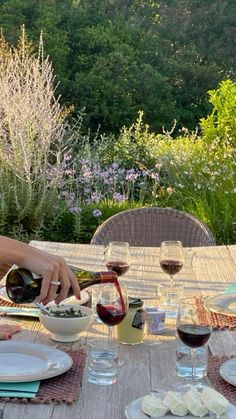 a person pouring wine into a bowl on top of a table with plates and glasses