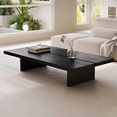 a modern living room with white furniture and plants in the window sill, along with a black coffee table