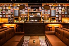 the inside of a restaurant with wooden shelves and leather couches