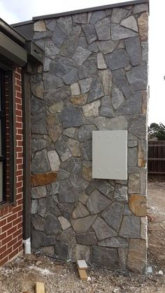 a brick building with a sign attached to it's side in front of a house