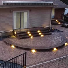 an outdoor patio with steps and lights on the side, surrounded by brick pavers