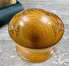 a wooden bowl sitting on top of a table next to an open book and a pair of scissors