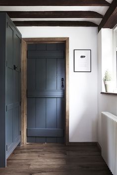 an empty hallway with blue painted doors and wood flooring, next to a radiator