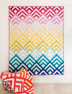 two quilts on the floor next to each other in front of a white wall