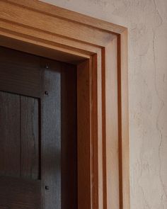 an open wooden door in a room with white walls and wood trimming on the wall