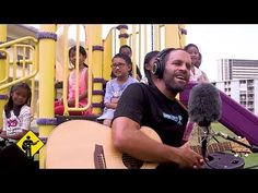 a man with headphones on sitting in front of a microphone while holding a guitar