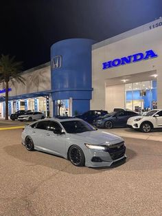 a honda dealership at night with cars parked in the parking lot and palm trees