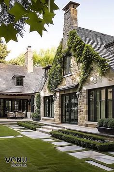 An elegant stone manor with ivy-covered walls, large windows, and a meticulously manicured lawn, showcasing a blend of classic architecture and lush greenery that exudes refined luxury. Manicured Lawn, Timeless Architecture, Mediterranean Villa, Mudroom Design