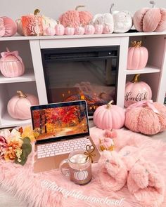 a laptop computer sitting on top of a pink fluffy blanket next to pumpkins and other decorations