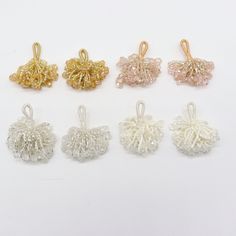 six different colored crochet ornaments on a white surface with gold and silver accents