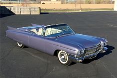 an old purple car parked in a parking lot