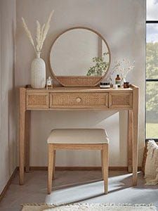 a wooden vanity table with a mirror and stool in front of it on top of a rug