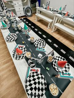 a long table with black and white checkered plates on it, along with other place settings