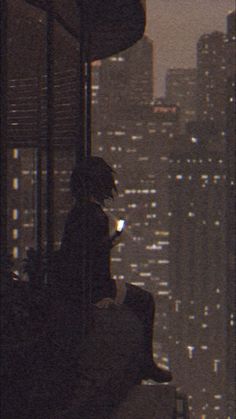 a man sitting on top of a building looking at his cell phone in the city