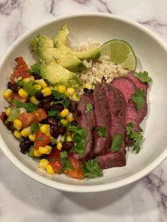 a white bowl filled with meat, rice and veggies on top of a marble counter