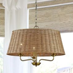 a wicker chandelier hanging from a ceiling in a room with white curtains