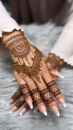 a woman's hand with henna tattoos on it