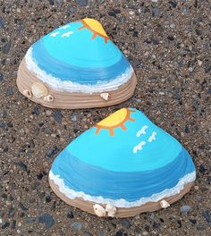 two painted wooden shoes sitting on top of a gravel covered ground next to each other