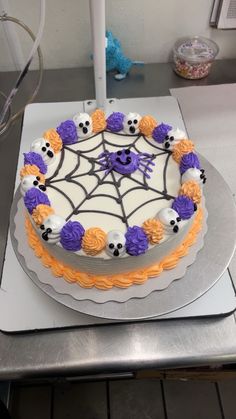 a cake decorated with icing and decorations on top of a metal tray in the shape of a spider web