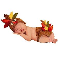 a baby wearing a turkey costume laying on it's side with its eyes closed