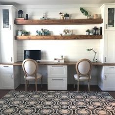 two chairs sitting at a desk with shelves above it and a rug on the floor