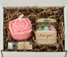 a pink rose in a glass jar next to a bottle of love you lotion